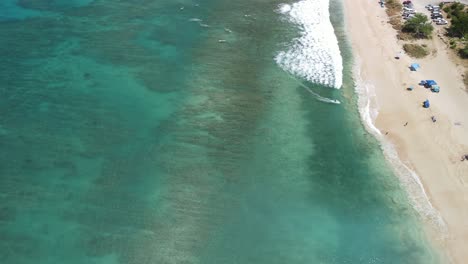 Aerial-view-of-surfers-riding-waves-with-the-reef-underneath-them