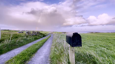 Private-driveway-in-rural-Cork-county,-Ireland-with-rainbow-and-dramatic-cloud-in-sky