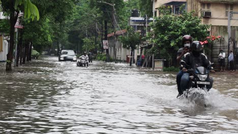 Bikes-and-car-getting-stuck-in-water-logged-street-during-heavy-rains-at-Kolkata,-India