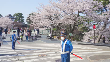 Maskierte-Verkehrspolizisten-Patrouillieren-Während-Der-Sakura-Saison-Im-Kenrokuen-Garten-–-Totale