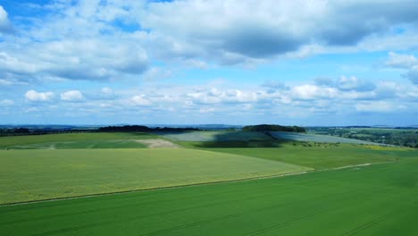 Static-aerial-view-of-green-farm-crops-in-Salisbury-Plains-with-clouds-in-England