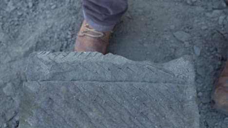 Handgehaltene-Top-Down-Aufnahme-Eines-Steinhandwerkers,-Der-Mit-Einem-Handpickel-Einen-Block-Aus-Cancagua-Stein-In-Der-Stadt-Ancud-Auf-Der-Insel-Chiloe-Formt