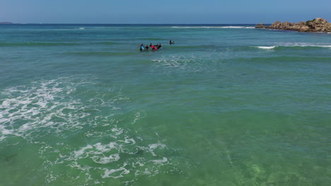 Aerial:-Kids-learn-to-surf-in-shallow-green-water-of-Australia's-coast