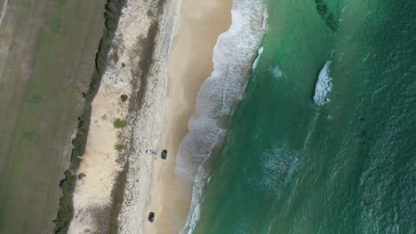 Aerial:-Three-trucks-on-sandy-Orchid-beach-on-Fraser-Island,-AUS