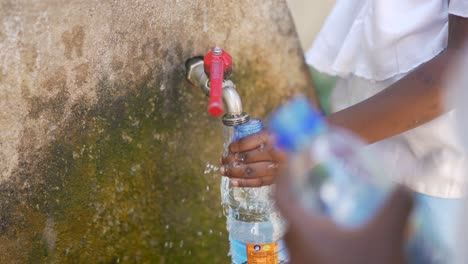 Close-up-cinematic-shot-of-African-black-children-filling-water-plastic-bottles-in-a-fountain