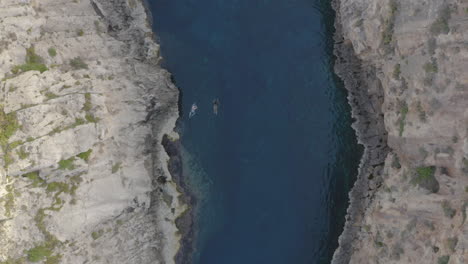 People-swimming-in-the-Wied-il-Għasri-sea-canyon,Malta,overhead-shot