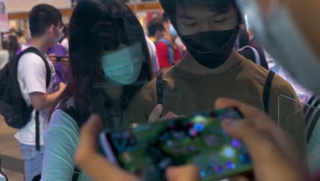 Una-Pareja-Juega-Videojuegos-En-Sus-Teléfonos-Inteligentes-Durante-El-Evento-De-Exhibición-Anicom-And-Games-Acghk-En-Hong-Kong