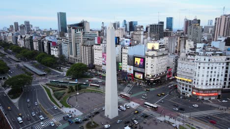 Toma-Aérea-Lenta-De-Tráficos-De-Intersecciones-Ocupados-Con-Densos-Edificios-Comerciales-Y-Residenciales-Y-Vallas-Publicitarias-En-La-Plaza-De-La-República-Con-La-Icónica-Estructura-Monumental-Del-Obelisco-En-El-Centro