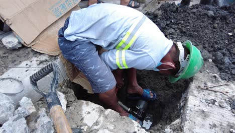 Foremen-wearing-safety-reflective-vests-used-their-shovel,-cement,-and-demolition-hammer-to-perform-deep-excavation-beside-the-road-and-gutter-for-installing-new-water-piping-from-the-main-water-line