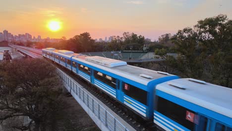 Train-heading-back-towards-city,-rides-into-beautiful-golden-sunset