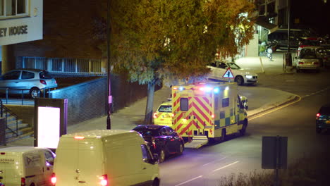London-ambulance-with-flashing-lights-parked-on-a-street-at-night-in-traffic