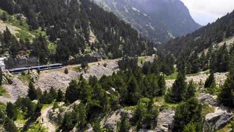 Luftbild:-Zahnradbahn,-Die-Durch-Ein-Grünes-Tal-Fährt,-Und-Einige-Wanderer-Auf-Einem-Weg