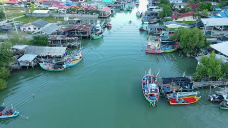 Steady-aerial-footage-of-this-fishing-village,-a-boat-seen-midway-going-in-the-river,-people-working-about