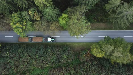 Tracking-a-tractor-with-two-trailers-from-above,-flying-with-a-drone-in-a-autumn-avenue