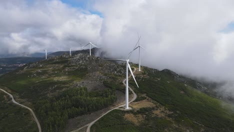 Mountain-shrouded-in-clouds-and-slowly-spinning-wind-turbines-blades