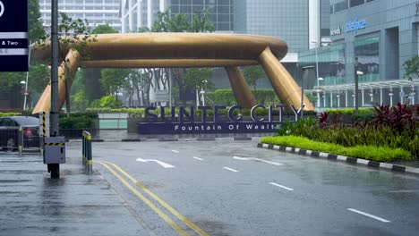 Car-traffic-at-Suntec-City-on-a-rainy-day,-Fountain-of-Wealth-in-Singapore