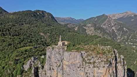 Castellane-France-Aerial-v1-drone-flying-around-historic-clifftop-chapelle-notre-dame-du-roc,-revealing-village-townscape-and-mountainous-landscape---July-2021