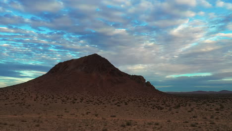 Orbiting-aerial-view-of-a-lone-butte-in-the-Mojave-Desert-with-a-colorful-sky-at-dusk