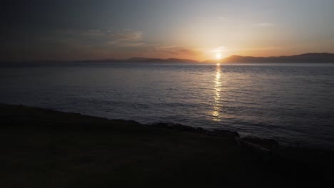 Filmischer-Blick-Auf-Den-Sonnenuntergang-Hinter-Der-Bergkette-Und-Dem-Meerwasser,-Statische-Ansicht