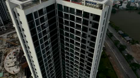 Descending-aerial-crane-shot-down-large-southeast-asian-residential-high-rise-housing-development-with-urban-sprawl-in-the-background