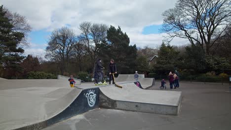 Kids-having-fun-on-scooters-in-a-public-outdoor-skate-park-during-springtime