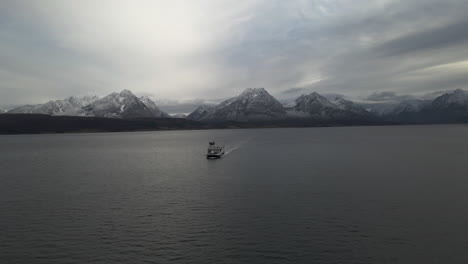 Aerial-view-of-scenic-arctic-landscape,-ferry-boat-cruising-with-Lyngen-Alps-background