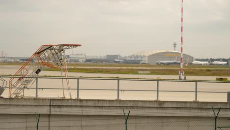 Airplane-take-off-at-at-Frankfurt-Airport-with-airport-stairs-in-forefront,-Germany-on-a-cloudy-day