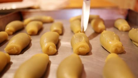 pinching-the-traditional-italian-stuffed-pastries-with-scissors-to-decorate-them,-close-up-shot