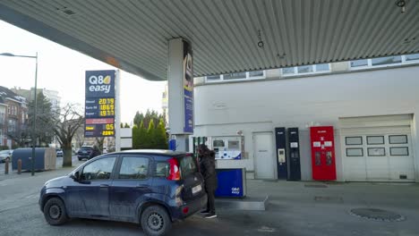 Middle-aged-woman-fills-car-with-diesel-at-gas-station-in-Brussels,-Belgium