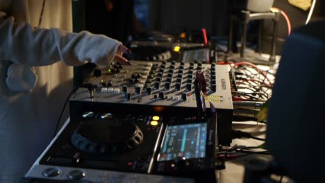 Right-hand-side-of-person-wearing-white-sweating-while-adjusting-and-tweaking-DJ-mixing-console-during-live-DJ-music-performance