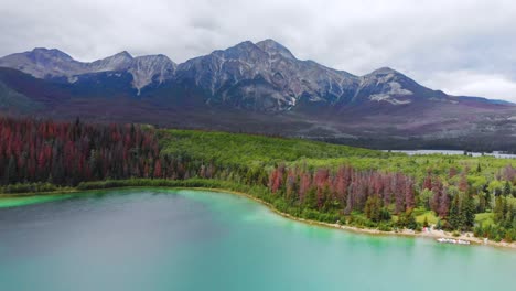 Lago-Maligne-Y-Montañas-En-El-Fondo,-Drone-Aéreo-Vuela-Hacia-Atrás-Vista-Del-Parque-Nacional-Jasper-En-Canadá,-Alberta