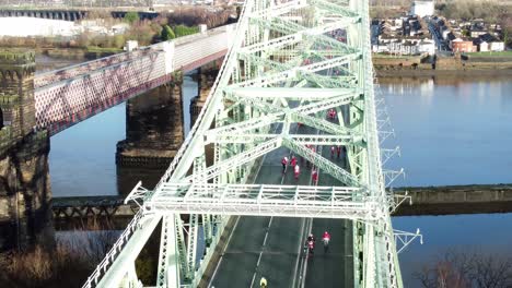 Charity-Santa-dash-fun-run-over-Runcorn-Silver-Jubilee-bridge-Aerial-view-push-in-tilt-up