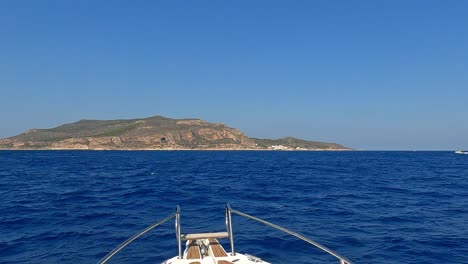 Bow-of-yacht-cruising-and-approaching-Levanzo-Sicilian-islan,-Sicily-in-Italy