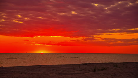 Atemberaubender-Rötlicher-Sonnenaufgang-über-Dem-Ruhigen-Meerwasser-Am-Strand,-Zeitrafferansicht