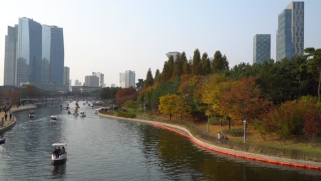 Menschen-Reisen-Im-Herbst-Bei-Sonnenuntergang-Mit-Familienbooten-Auf-Einem-See-Im-Songdo-Central-Park