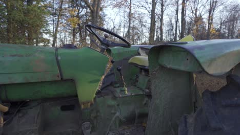 Toma-Panorámica-De-Un-Viejo-Tractor-Agrícola-Vintage-En-Un-Bosque,-Máquina-Verde-John-Deere