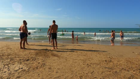 Group-of-friends-have-fun-playing-beach-soccer-on-seashore-at-Punta-Penna-in-Abruzzo,-Italy