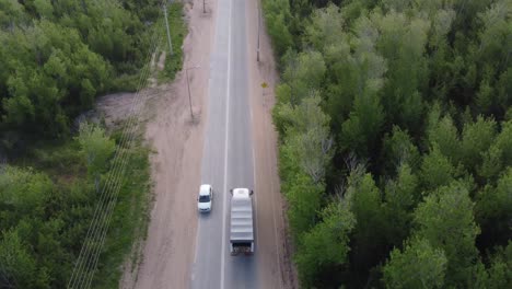 Aerial-view-of-driving-truck-on-rural-road-in-Argentina-surrounded-by-green-forest-trees-during-daytime