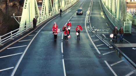 Charity-Santa-dash-funny-musical-marching-drummer-band-Runcorn-Silver-Jubilee-bridge-Aerial-view-push-in