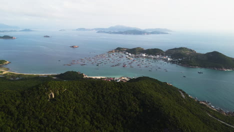 Luftaufnahme-Der-Insel-Binh-Hung-Mit-Vielen-Verankerten-Booten-In-Der-Bucht-Mit-Epischer-Berglandschaft-Und-Meer-In-Vietnam