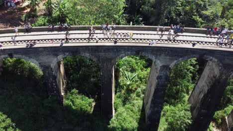 Zurückziehende-Aufnahme-Von-Touristen,-Die-Sich-Auf-Die-Eisenbahnbrücke-Mit-Neun-Bögen-Legen,-Demodara,-Sri-Lanka