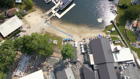 Aerial-view-overlooking-the-building,-beach-and-dock-at-the-Indian-Ranch,-in-Webster,-USA---tilt,-drone-shot