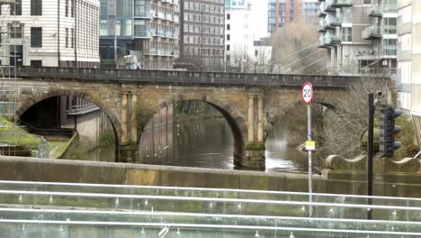 Manchester-old-industrial-arched-canal-bridge-female-crossing-modern-glass-footbridge