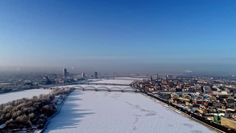 Aerial-view-over-frozen-Daugava-River-in-winter,-snowy-Riga-city