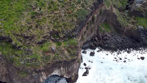 Top-down-birdseye-aerial-drone-view-of-dramatic-cliffs-dropping-into-the-stormy-ocean