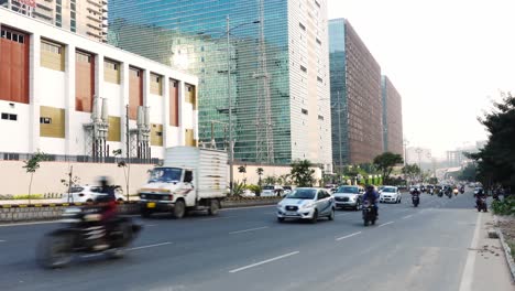 Blick-Auf-Die-Fahrzeuge,-Die-Sich-An-Einem-Sommertag-In-Hyderabad-Auf-Der-Autobahn-Vor-Den-Hohen-Bürogebäuden-Bewegen