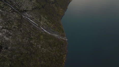 Topdown-Des-Wasserfalls,-Der-Aus-Steilen-Felsigen-Bergen-Im-Fjord-An-Der-Westküste-Norwegens-Fließt
