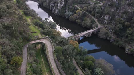 View-of-a-roman-bridge-and-stone-path-and-reflection-of-clouds-in-the-river---drone-view