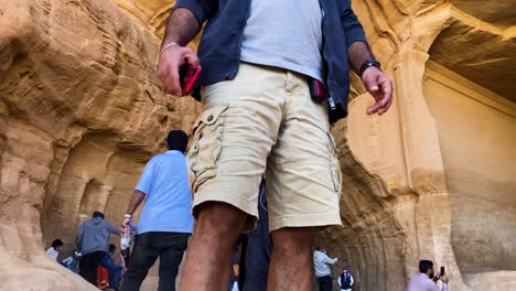 Anonymous-Tourists-Taking-Pictures-Of-Two-Huge-Facing-Rocks,-The-Wonder-Of-Al-Ula-Saudi-Arabi-Tilt-Low-Angle-Shot