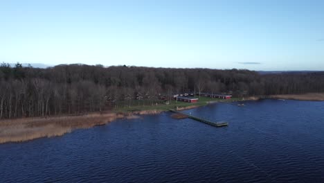 Drone-Footage-Scandinavian-Lake's-Shoreline,-Marina-with-a-Pier-and-a-Forest---Truck-Shot-and-Panning-Shot